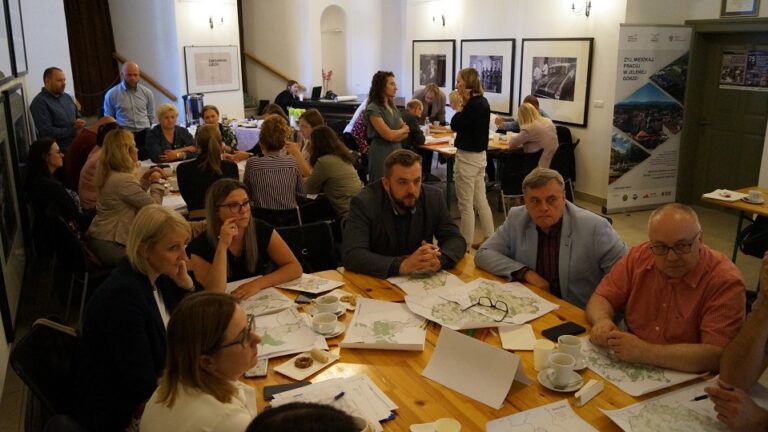 Spotkanie Zespołu, na pierwszym planie grupa osób przy stole z planami Aglomeracji Jeleniogórskiej.